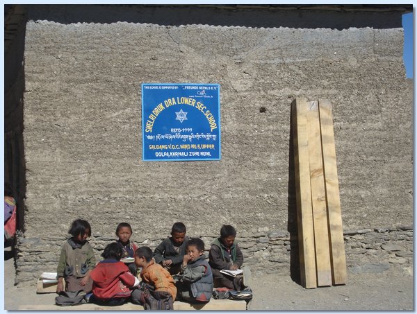 Einige Schueler in der Pause unter dem neuen Schulschild, das Freunde Nepals wuerdigt.JPG